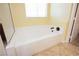 Bathroom featuring a white tub with tile surround, window, and tan flooring at 4208 Lower Saxon Ave, North Las Vegas, NV 89085