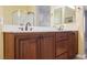 Close-up of bathroom vanity with wood cabinets, double sinks, and classic fixtures at 4208 Lower Saxon Ave, North Las Vegas, NV 89085