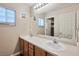 Bathroom featuring double sinks, wood cabinets, a large mirror, and updated lighting at 6891 Nickel Mine Ave, Las Vegas, NV 89122