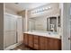 Bathroom featuring double sinks, wood cabinets, a large mirror, and updated lighting at 6891 Nickel Mine Ave, Las Vegas, NV 89122