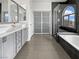 Modern bathroom featuring a double vanity, a bathtub, and a glass-enclosed shower with gray tiles at 7110 Brighton Village St, Las Vegas, NV 89166
