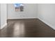 A minimal bedroom space, featuring dark wood floors, white walls, and natural light at 7110 Brighton Village St, Las Vegas, NV 89166