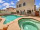 A backyard pool and hot tub, enclosed by a safety fence, with an attached two-story house at 7110 Brighton Village St, Las Vegas, NV 89166