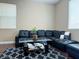 Cozy living room featuring a black leather sectional, glass table, and patterned rug at 7735 Pista Way, Las Vegas, NV 89179