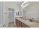 Bathroom features double sinks, granite countertops, wood cabinets, and a view to the shower at 780 Flowing Meadow Dr, Henderson, NV 89014