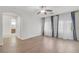 Spacious bedroom with hardwood floors, curtains on the windows and an arched doorway to the bathroom at 780 Flowing Meadow Dr, Henderson, NV 89014