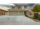 Charming two-story home showcasing a well-manicured lawn, stone accents, and a spacious three-car garage at 780 Flowing Meadow Dr, Henderson, NV 89014