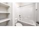 Well-lit bathroom featuring a shower-tub combo, white tile, and open shelving at 8629 Ensworth St # 111, Las Vegas, NV 89123