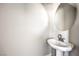 Bright half bathroom features a pedestal sink and round mirror, perfect for guests at 8629 Ensworth St # 111, Las Vegas, NV 89123