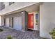 Modern home featuring a gray exterior, two-car garage, brick paver driveway, and a vibrant orange front door at 8629 Ensworth St # 113, Las Vegas, NV 89123