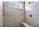 Modern tiled shower with gray tiling, a shower head and bench, and a small window at 8629 Ensworth St # 113, Las Vegas, NV 89123