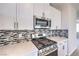 Close up of stainless gas range with mosaic tile backsplash and white cabinets at 8629 Ensworth St # 113, Las Vegas, NV 89123
