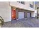 Paver driveway leading to a two-car garage and a red-framed glass door with modern landscaping at 8629 Ensworth St # 114, Las Vegas, NV 89123