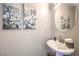 Stylish powder room features a pedestal sink, decorative mirror, and elegant floral artwork, adding a touch of sophistication at 8629 Ensworth St # 114, Las Vegas, NV 89123