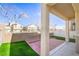 View of backyard with partial patio, grass, and retaining wall separating property from other homes at 8798 Tom Noon Ave # 103, Las Vegas, NV 89178