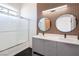 Modern bathroom featuring a double sink vanity, round mirrors, and a glass-enclosed shower at 8798 Tom Noon Ave # 103, Las Vegas, NV 89178