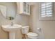 Bathroom featuring a pedestal sink, toilet, shuttered window, and modern fixtures provides a functional space at 9108 Ghost Mountain Ave, Las Vegas, NV 89129
