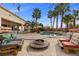This backyard features a pool, palm trees, patio furniture, and a circular stone fire pit at 9475 Castillana Ct, Las Vegas, NV 89147