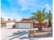 Two-story home with a two-car garage and a large palm tree in the front yard under a partly cloudy sky at 1009 N Tenaya Way, Las Vegas, NV 89128