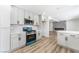 Updated kitchen features modern appliances, white cabinets, a breakfast bar, and light wood-look flooring at 1009 N Tenaya Way, Las Vegas, NV 89128