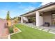 Backyard featuring covered patio with seating, an artificial lawn, hardscape, and lush landscaping at 10794 White Clay Dr, Las Vegas, NV 89135