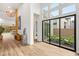 Bright entryway with modern decor, light wood floors, and view to backyard patio seating through large glass sliding doors at 10794 White Clay Dr, Las Vegas, NV 89135