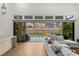 Stylish living room with hardwood floors, a comfortable sofa, and scenic backyard views through large windows at 10794 White Clay Dr, Las Vegas, NV 89135