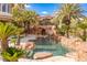 Luxury pool features a water slide built into rock features surrounded by palm trees at 2540 Red Arrow Dr, Las Vegas, NV 89135