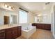 Bright bathroom featuring double sinks, a soaking tub, and rich wood cabinetry, creating a spa-like atmosphere at 2824 Shadows Edge Ct, Henderson, NV 89052