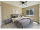 Staged bedroom with large window, ceiling fan, gray furnishings, and wood grain flooring at 3080 S Prairie Ave, Pahrump, NV 89048