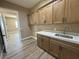 Laundry room with wood cabinetry, countertop space, and a sink with modern fixtures at 3080 S Prairie Ave, Pahrump, NV 89048