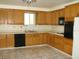 Functional kitchen with oak cabinets, tile floors, black appliances, and a window above the sink at 313 View Dr, Las Vegas, NV 89107