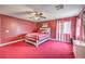 Spacious bedroom with red carpet, a ceiling fan, and natural light from the windows at 5032 Dancing Lights Ave, Las Vegas, NV 89130