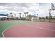 A multi-use green and maroon basketball court with palm trees is encased in a black fence under a cloudy sky at 6913 Evening Orchid St, North Las Vegas, NV 89086