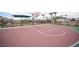Green and maroon basketball court with palm trees, backboards, and black fence under slightly cloudy skies at 6913 Evening Orchid St, North Las Vegas, NV 89086