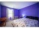 Cozy bedroom showcasing bright purple walls, carpeted floors, and a comfortable floral patterned bedspread at 6913 Evening Orchid St, North Las Vegas, NV 89086
