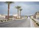 View of the community entrance featuring lush palms and paved roads, complemented by a gated entry at 6913 Evening Orchid St, North Las Vegas, NV 89086