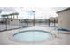 Hot tub surrounded by pool area with lounge chairs and palm trees. Community pool and clubhouse in background at 6913 Evening Orchid St, North Las Vegas, NV 89086