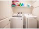 A clean laundry room is furnished with a stacked washer and dryer set, along with upper shelving for storage at 6913 Evening Orchid St, North Las Vegas, NV 89086