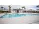 Community pool area with a large pool, lounge chairs, palm trees, and a clubhouse. Fenced for safety at 6913 Evening Orchid St, North Las Vegas, NV 89086