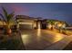Stunning exterior showcases desert landscaping, a large driveway, and warm lighting enhancing the home's curb appeal at 7682 Rafter Ct, Las Vegas, NV 89139