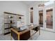 Bright home office features glass top desk, open shelving, and outdoor access through double doors at 7682 Rafter Ct, Las Vegas, NV 89139