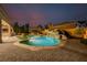 Beautiful backyard pool with rock waterfall feature and covered outdoor seating at dusk at 7682 Rafter Ct, Las Vegas, NV 89139