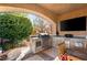 Outdoor kitchen area featuring a built-in grill, TV, counter space, and storage, great for outdoor cooking and entertaining at 8455 Stange Ave, Las Vegas, NV 89129