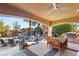 Inviting outdoor living space featuring a covered patio, outdoor kitchen, dining area, and pool with a rock waterfall feature at 8455 Stange Ave, Las Vegas, NV 89129