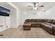 Living room featuring a brown sectional sofa, ceiling fan, and tile flooring at 9132 Gabardine Ave, Las Vegas, NV 89149
