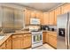 Well-lit kitchen featuring stainless steel refrigerator and wooden cabinets with granite countertops at 9844 Altadena St, Las Vegas, NV 89183