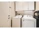A well-lit laundry room with white washer and dryer, cabinets, and a nearby door at 9844 Altadena St, Las Vegas, NV 89183