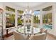 Bright dining area features a glass table, modern lighting, and expansive windows overlooking the pool at 10404 Longwood Dr, Las Vegas, NV 89134