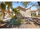 Beautiful home exterior with mature landscaping, including palm trees and desert plants, offering a serene outdoor setting at 10404 Longwood Dr, Las Vegas, NV 89134